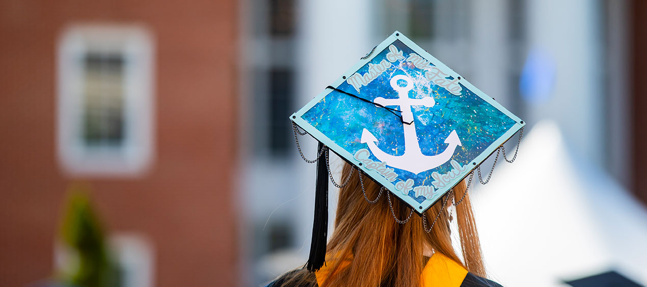 Graduate from the rear with a decorated cap that has an anchor on it and says 'master of my fate captain of my soul'
