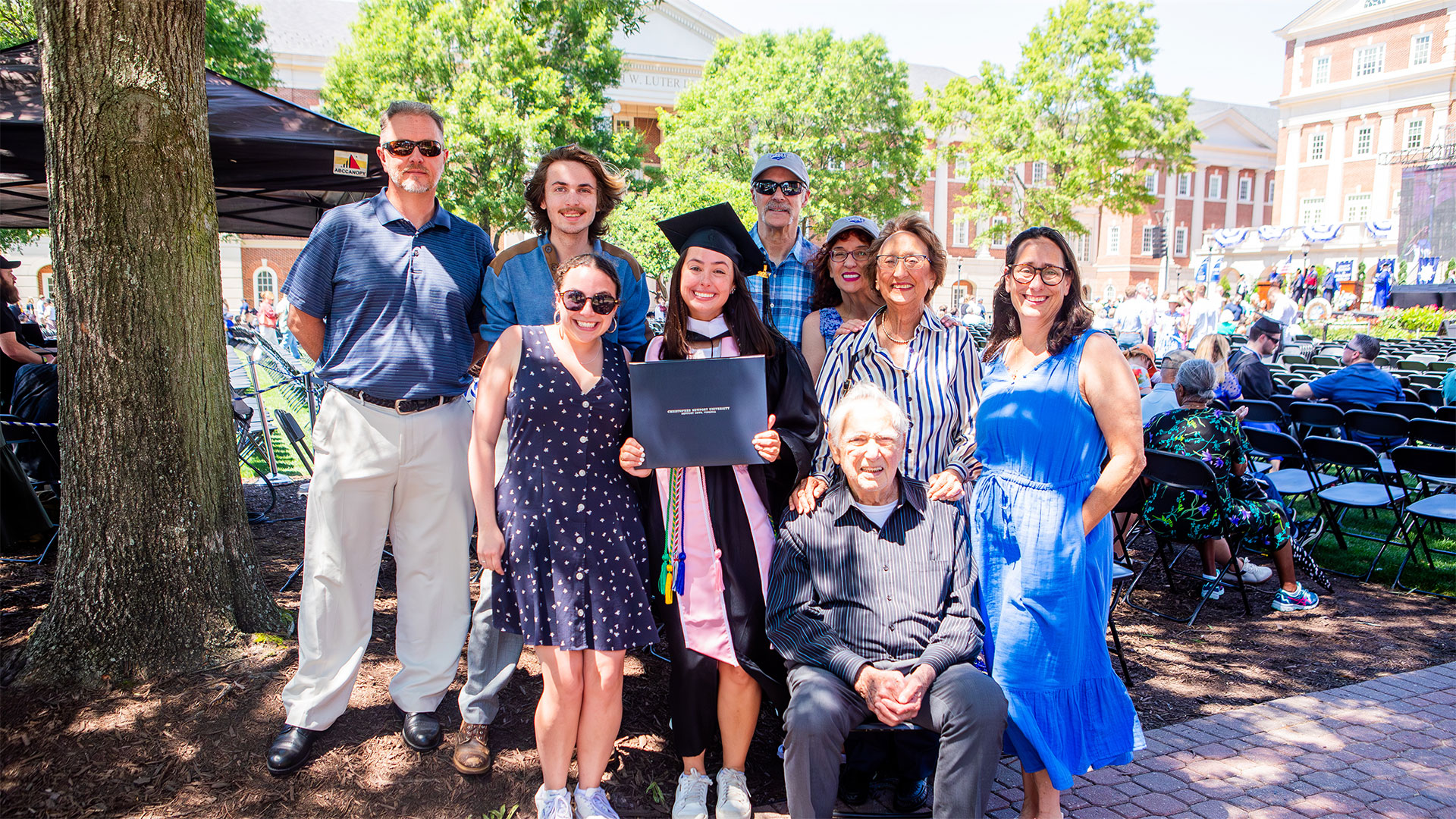 A graduate of CNU holds her diploma in the center while surrounded by family