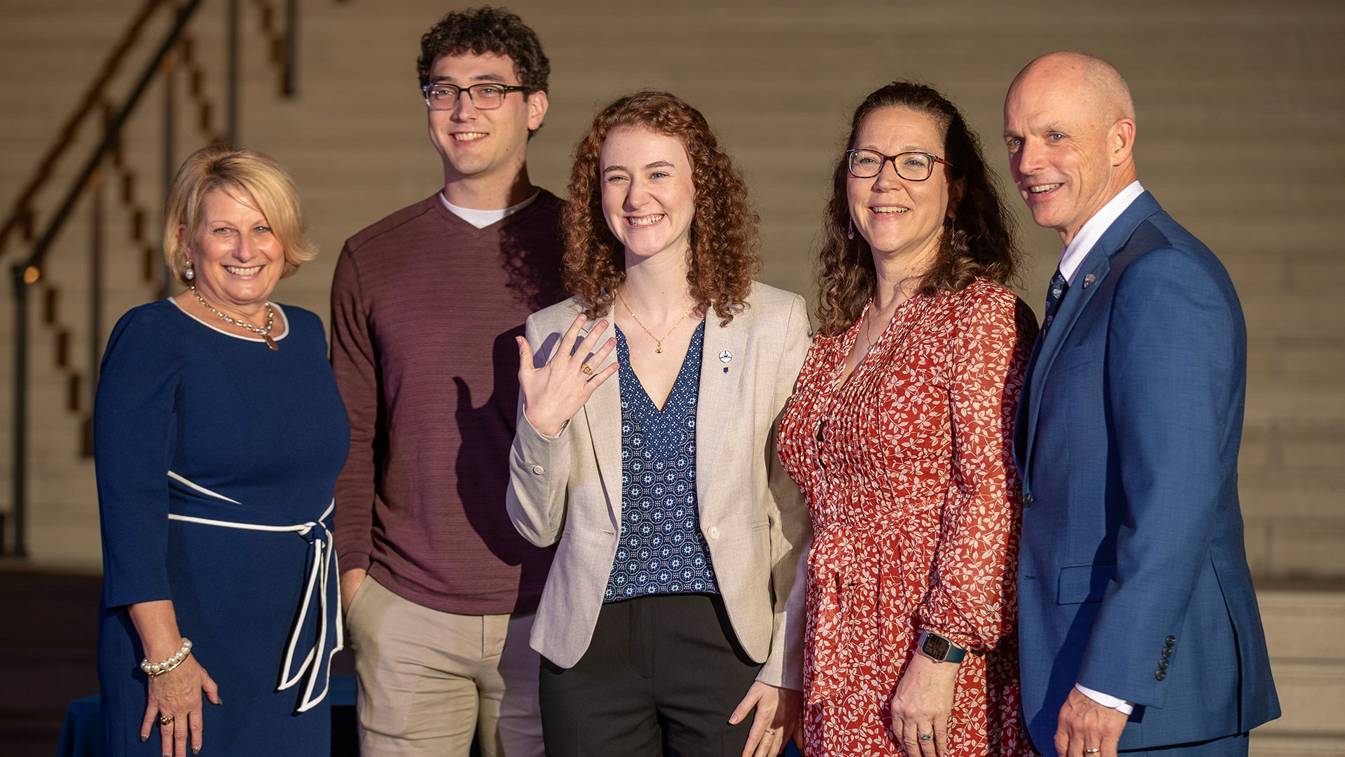 A student stands amongst family and CNU President and First Lady Bill and Angie Kelly while showing off her class ring.