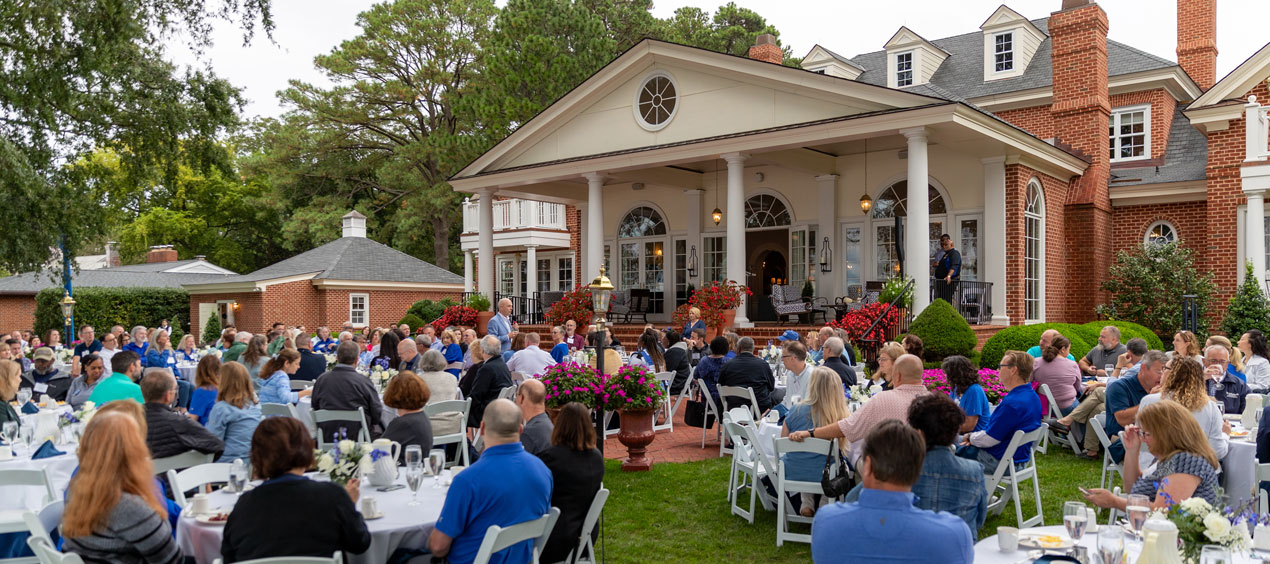 People gather outside of the Alumni House at an event