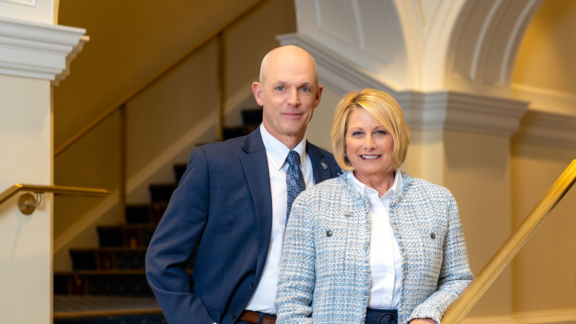 President and Mrs. Kelley stand together on a staircase.
