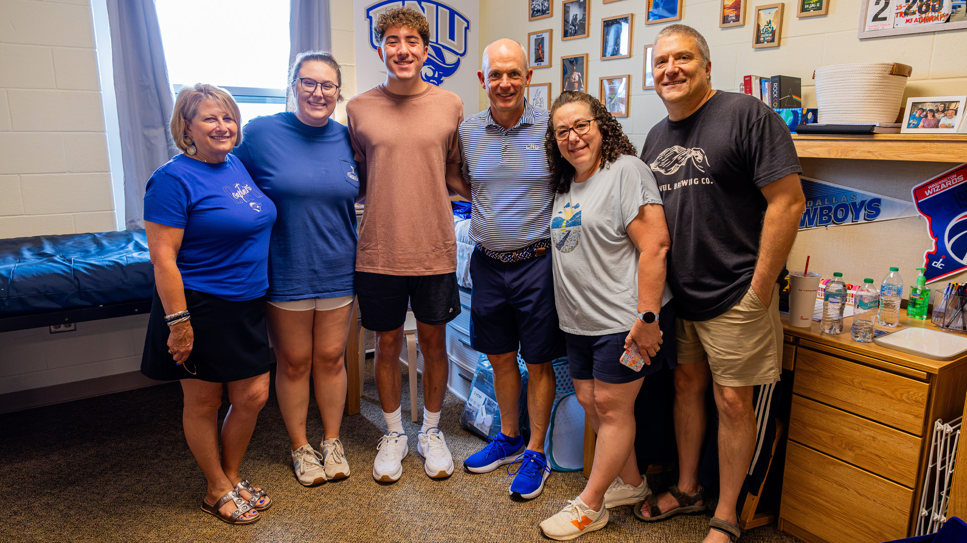 CNU President Bill Kelly and First Lady Angie Kelly stand with a family of four moving in a student.