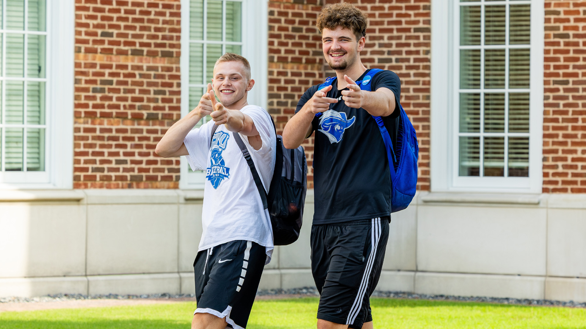 Two students wearing Captains athletic gear point finger guns at the camera
