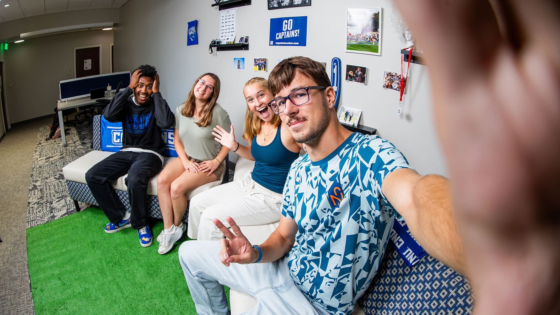 The four members of CNU On the Lawn student-run podcast team sitting on a couch taking a selfie