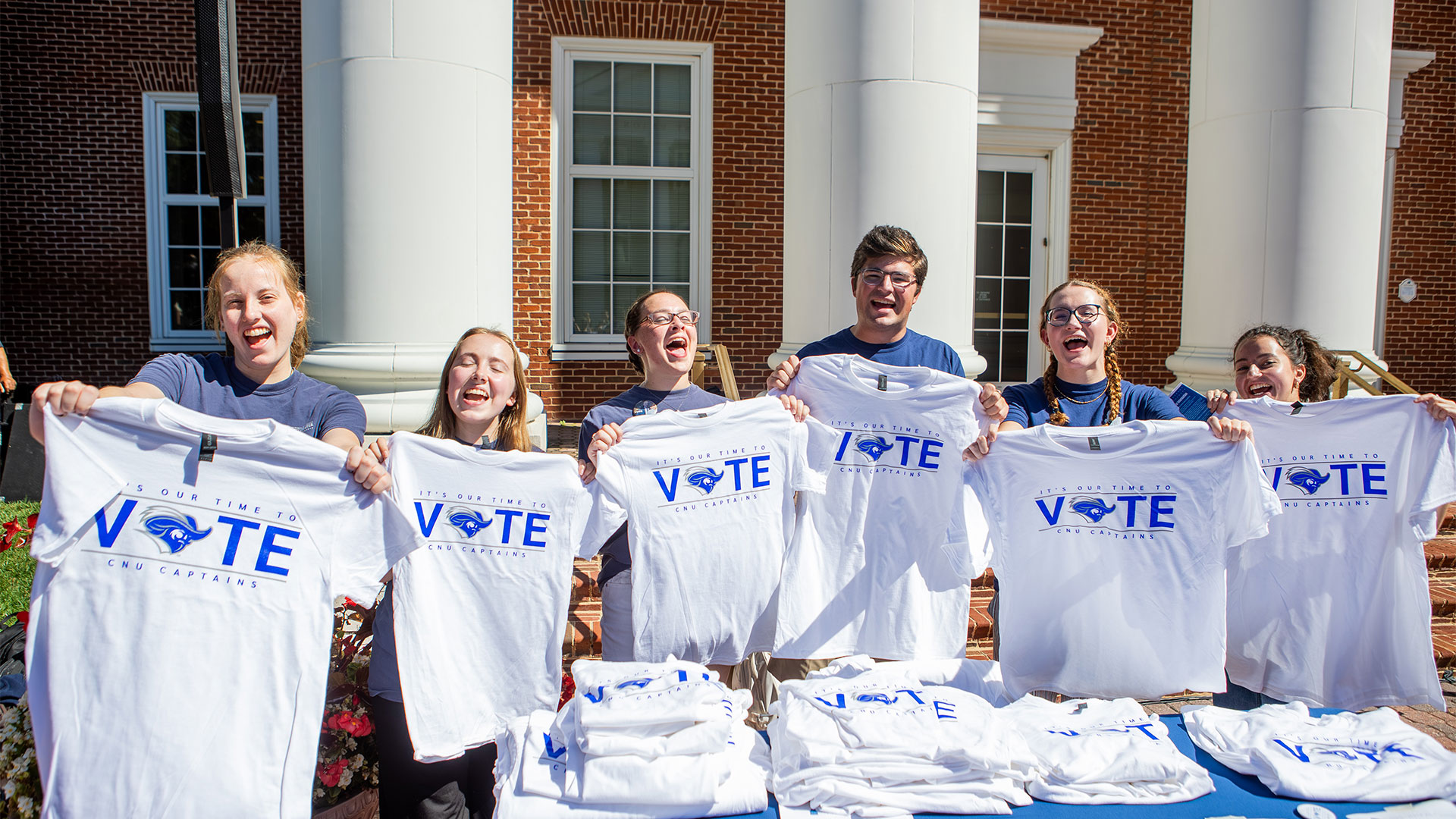 A group of students pose for a photo holding Captains Vote t-shirts