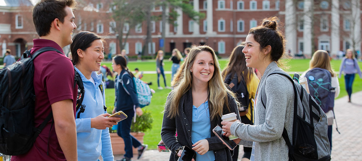 Group of four students laghing and talking on the Great Lawn