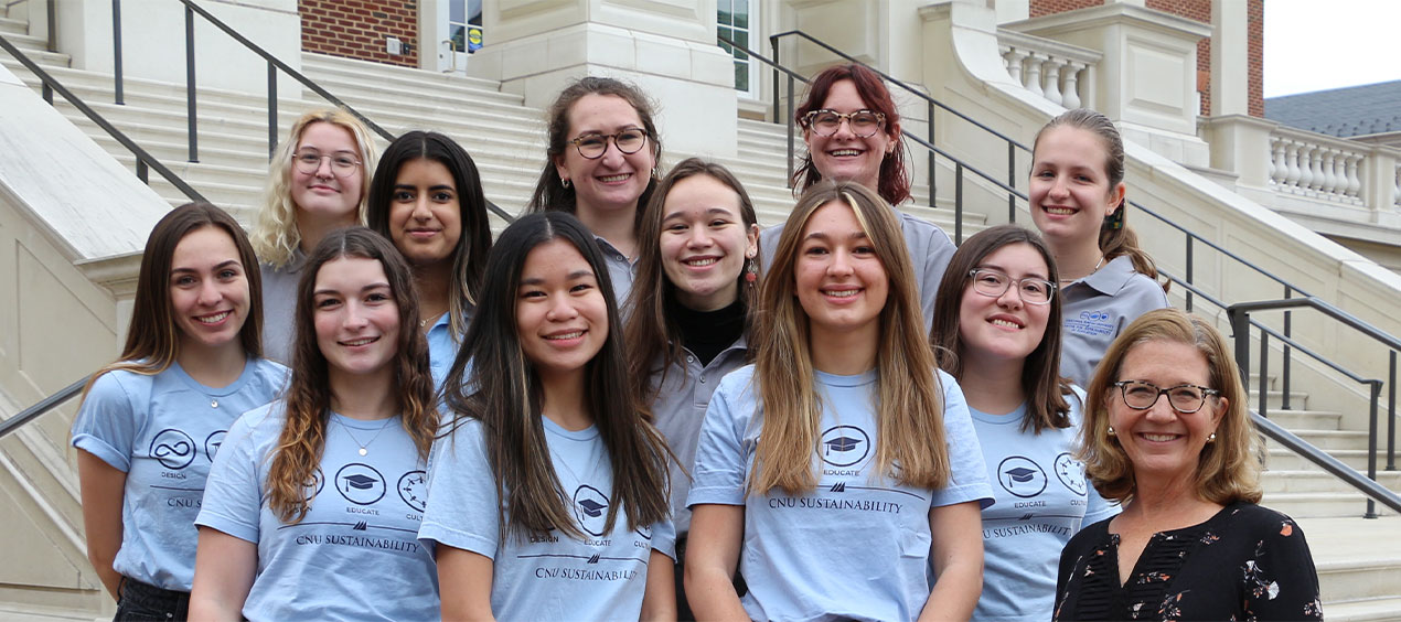 Student wearing Center for Sustainability in Education shirts standing on the steps of Christopher Newport Hall