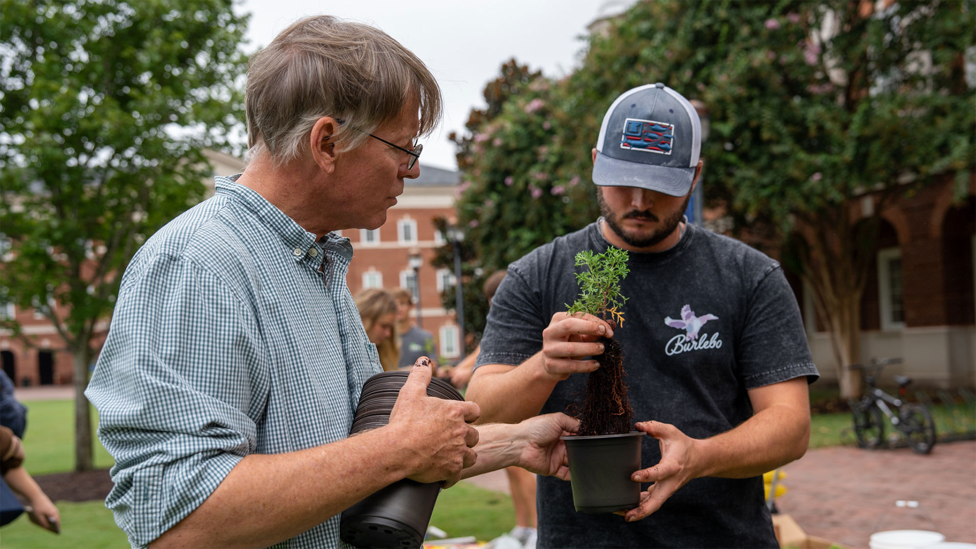 Professor Rob Atkinson works with a student to plant an Atlantic Cedar seedling.