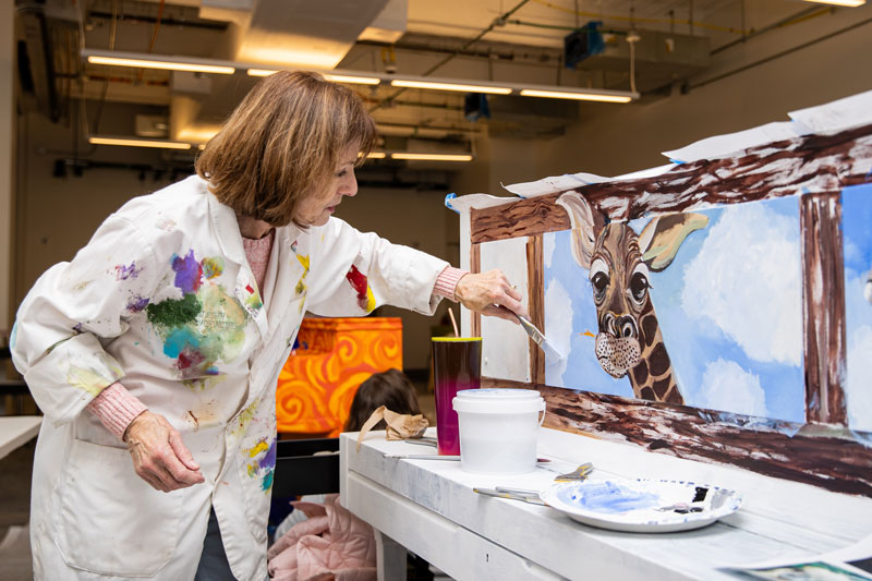 Terry Cox-Joseph paints a giraffe onto a piano