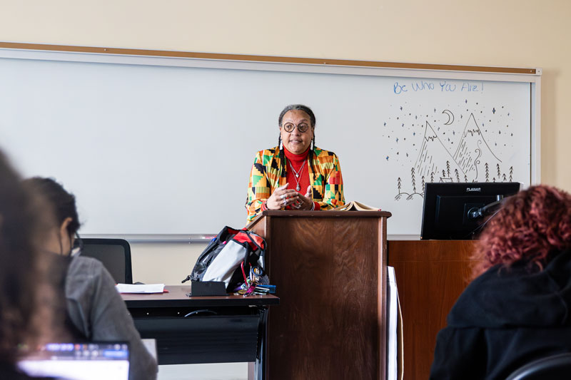 Dr. Pat Hopkins stands at the lectern while addressing students in her class.