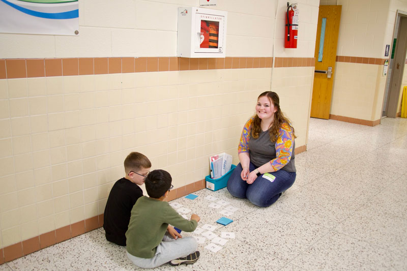 Laney Carnahan works with young students in the hallway