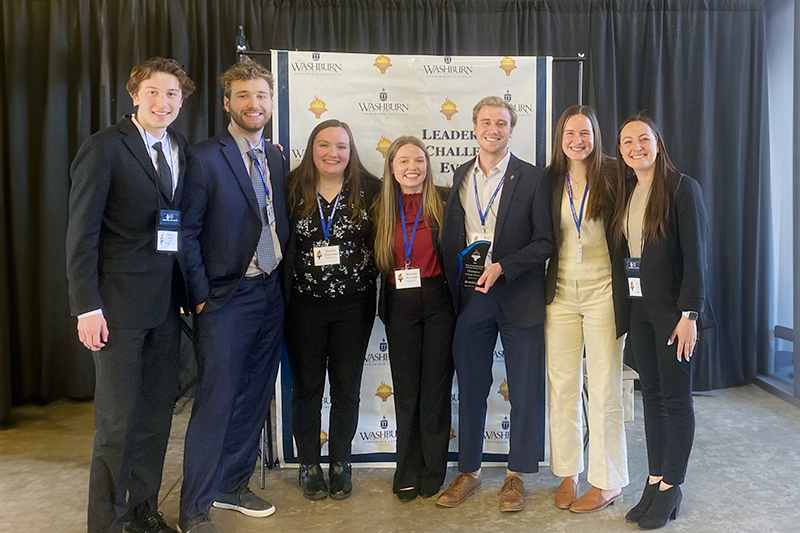 A group of students pose together with their trophy