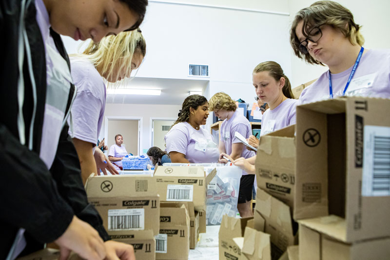 A group of students in lilac t-shirts create kits for victims of sexual assault at the Fear2Freedom offices.
