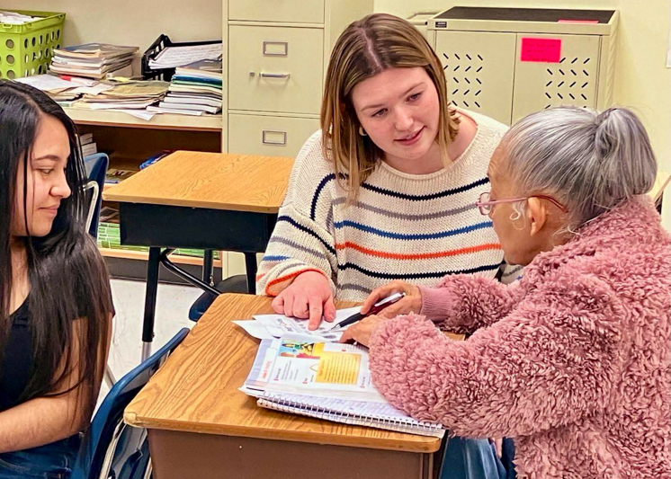 A student, center, assists students working on GED coursework.