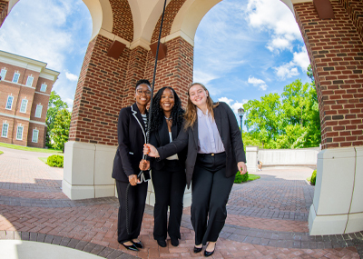 three students ringing the bell together