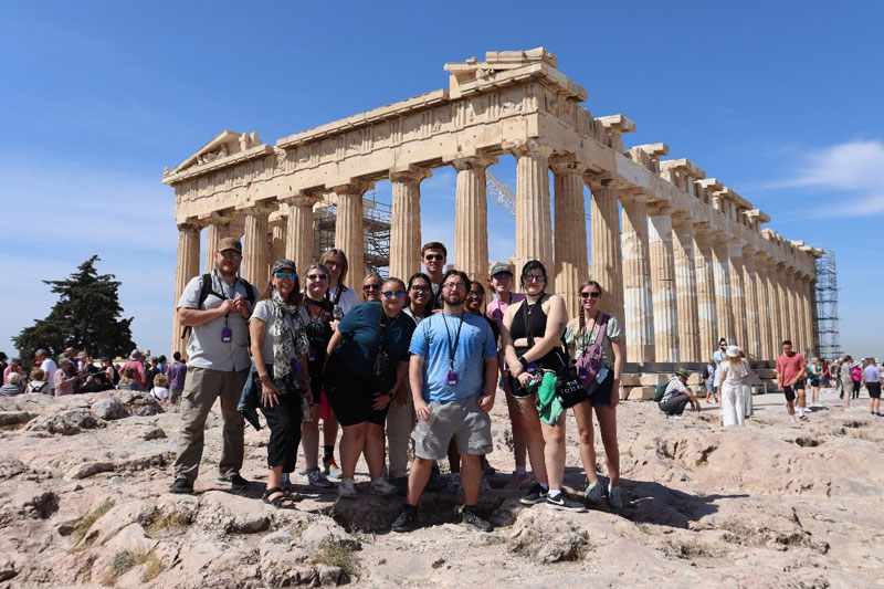 Students gather together to take a photo in front of the Acropolis. 