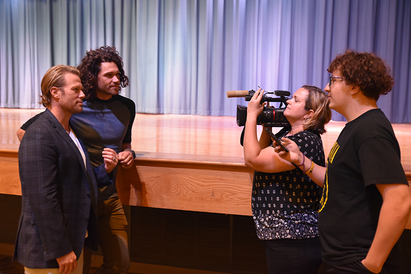 Jacob Young and Trent Garrett speak with a student while a person films