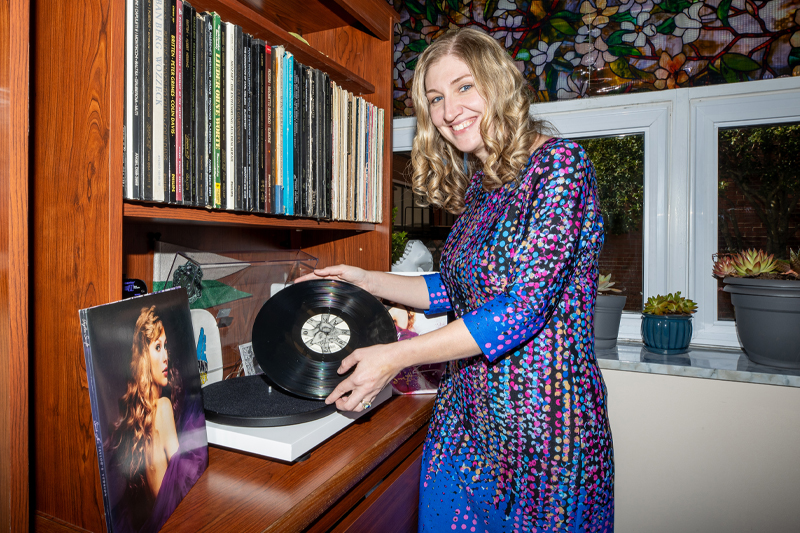 Dr. Chelsey Hamm holds a Taylor Swift vinyl album with the album cover to the right.