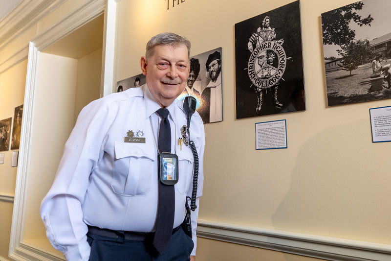 Kenneth Flick stands beside a picture of the seal he designed for the university.