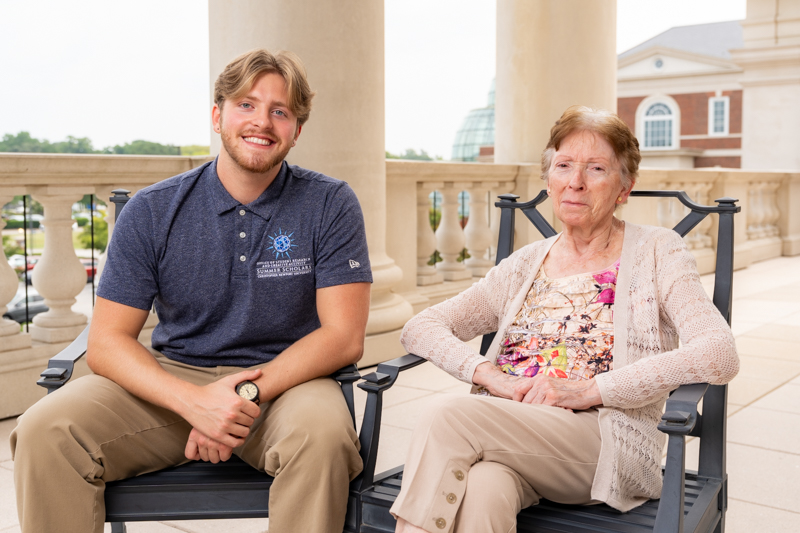 Sevrin VanDevender and Yaya sit in rocking chairs on the balcony of Christopher Newport Hall.