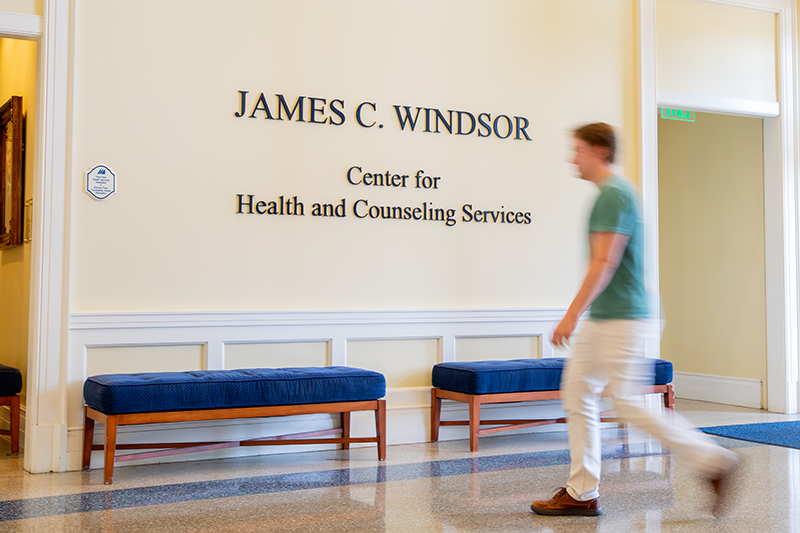 An out of focus student walks past the Office of Counseling Services.