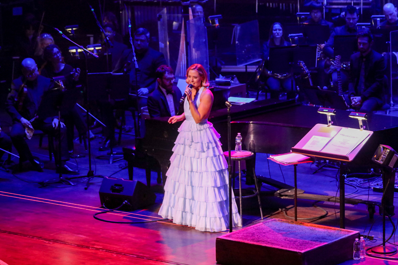 Erika Henningsen stands in the spotlight with members of the Virginia Symphony Orchestra behind her