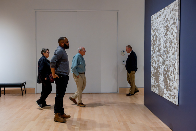 Individuals stand in the Anne Noland Edwards Gallery to view artwork in the Torggler Fine Arts Center.