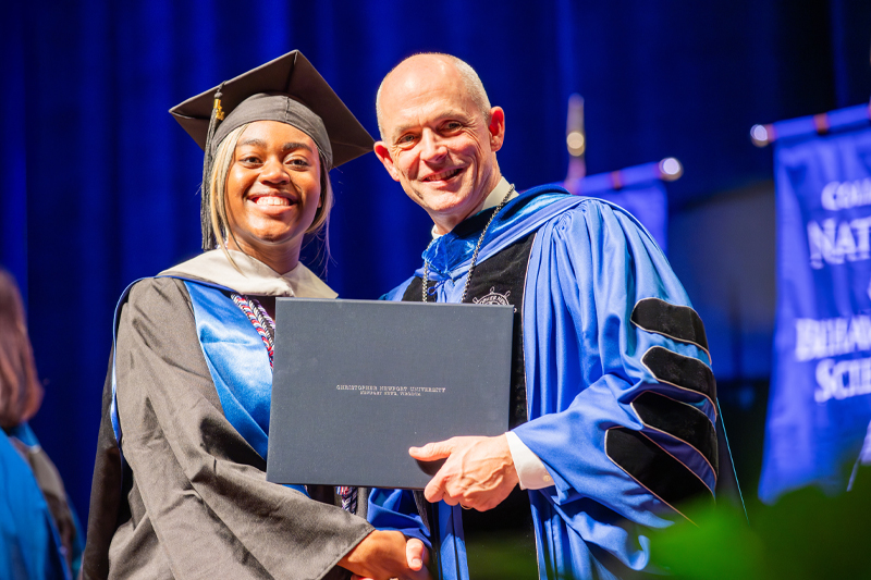 A Community Captain poses with CNU President William G. Kelly after receiving their diploma.