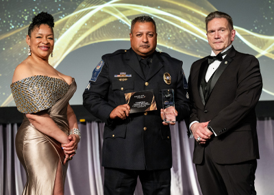 Delgado stands on stage with a man and woman after receiving the award