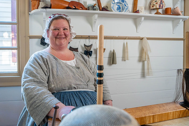 Debbie Turpin in Colonial era clothing in her wig shop in Colonial Williamsburg