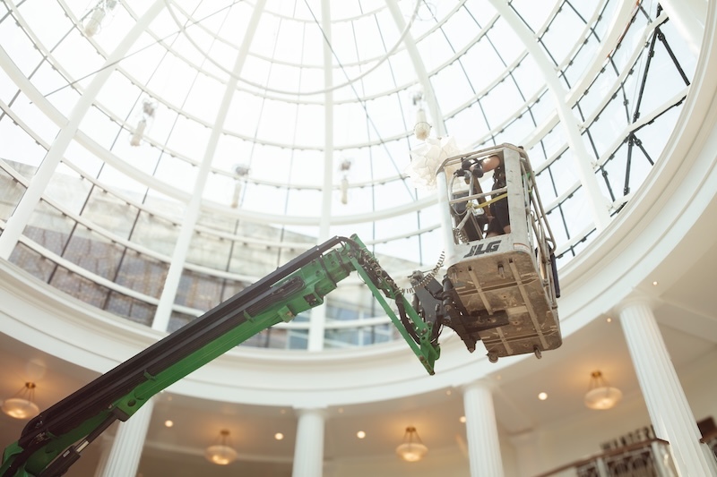 Daniel Marshall works from a cherry picker to clean and update settings for Shylight in the dome of the Torggler Fine Arts Center