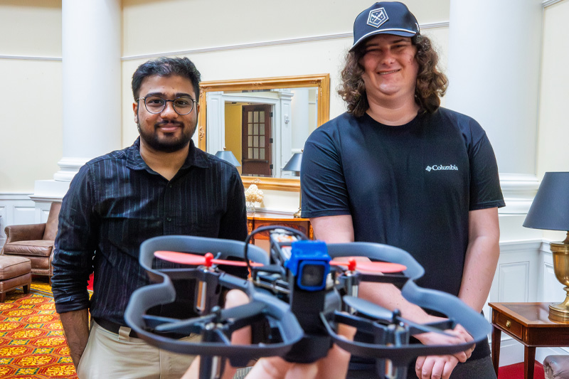 Dr. Abhishek Phadke and Cole Thomsen with a drone in the foreground.