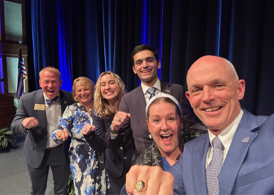 President and Mrs. Kelly pose with their new rings with Alumi staff