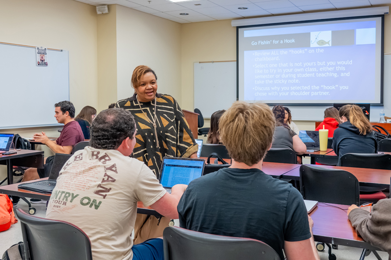 A professor talks with a student whose back is to us.