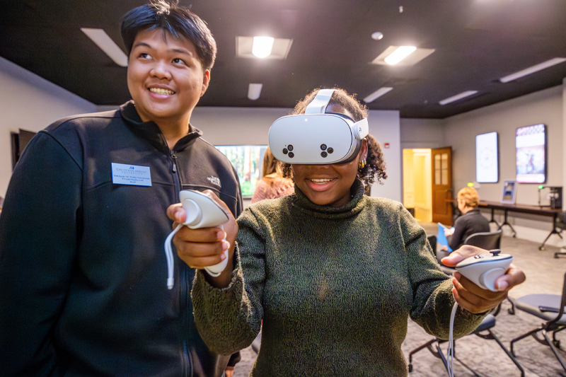 Two students smiling while using virtual reality headset