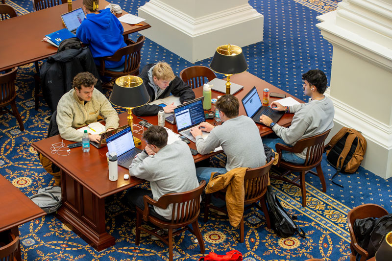  Gemini said Students at Christopher Newport University study at long wooden tables with laptops and lamps in a library.