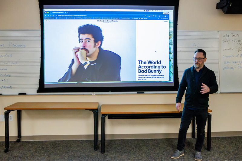 Dr. Mike Levine speaking in front of a presentation of Bad Bunny