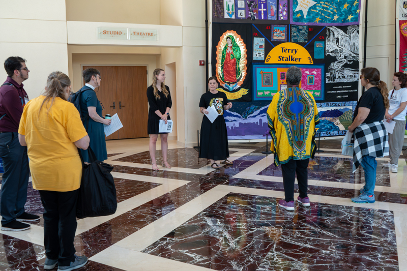 Dr. Brooke Covington and Charlotte Costic '27 (left) discuss the AIDS Memorial Quilt with attendees of the Hampton Roads Social Justice Conference.