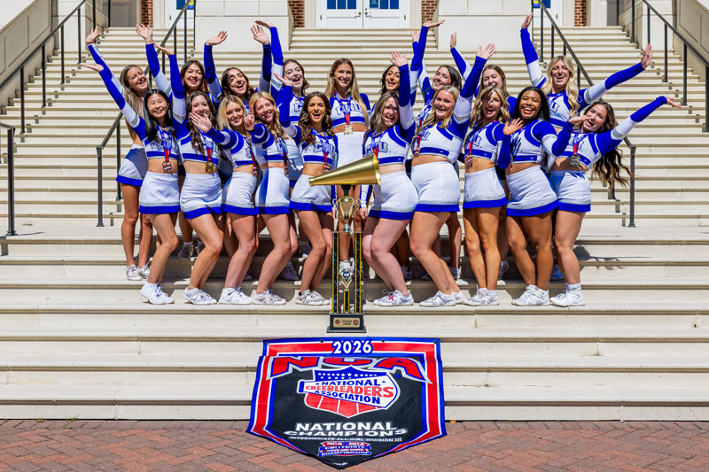 Members of CNU's Competitive Cheerleading squad pose with their trophy that has a golden megaphone on top. Their national champion banner underneath