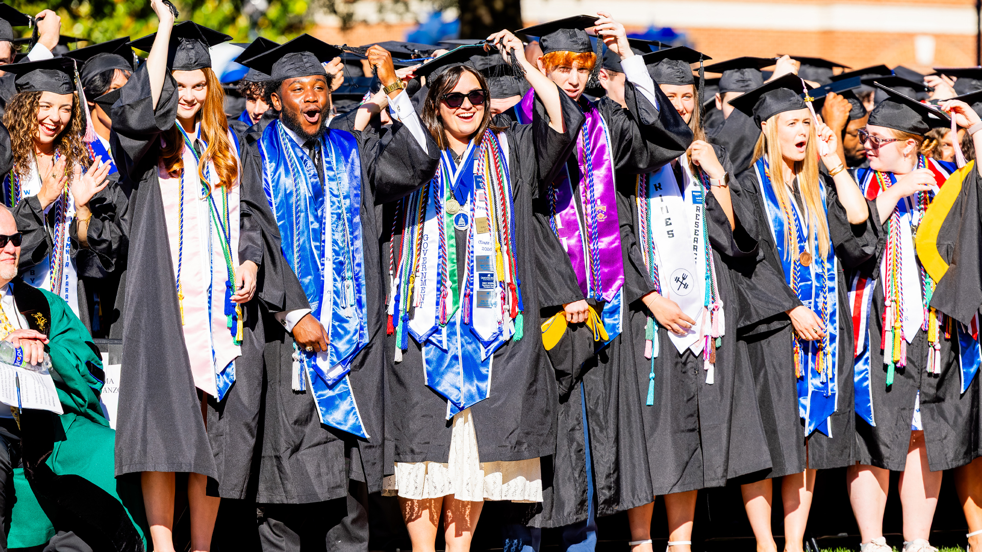 Students wearing graduation regalia turn their tassels during the conferring of degrees.