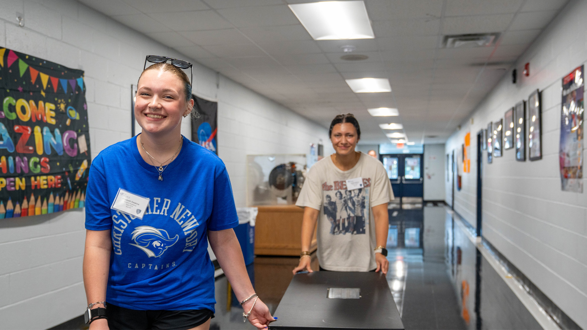 Two students pushing a cart in a school