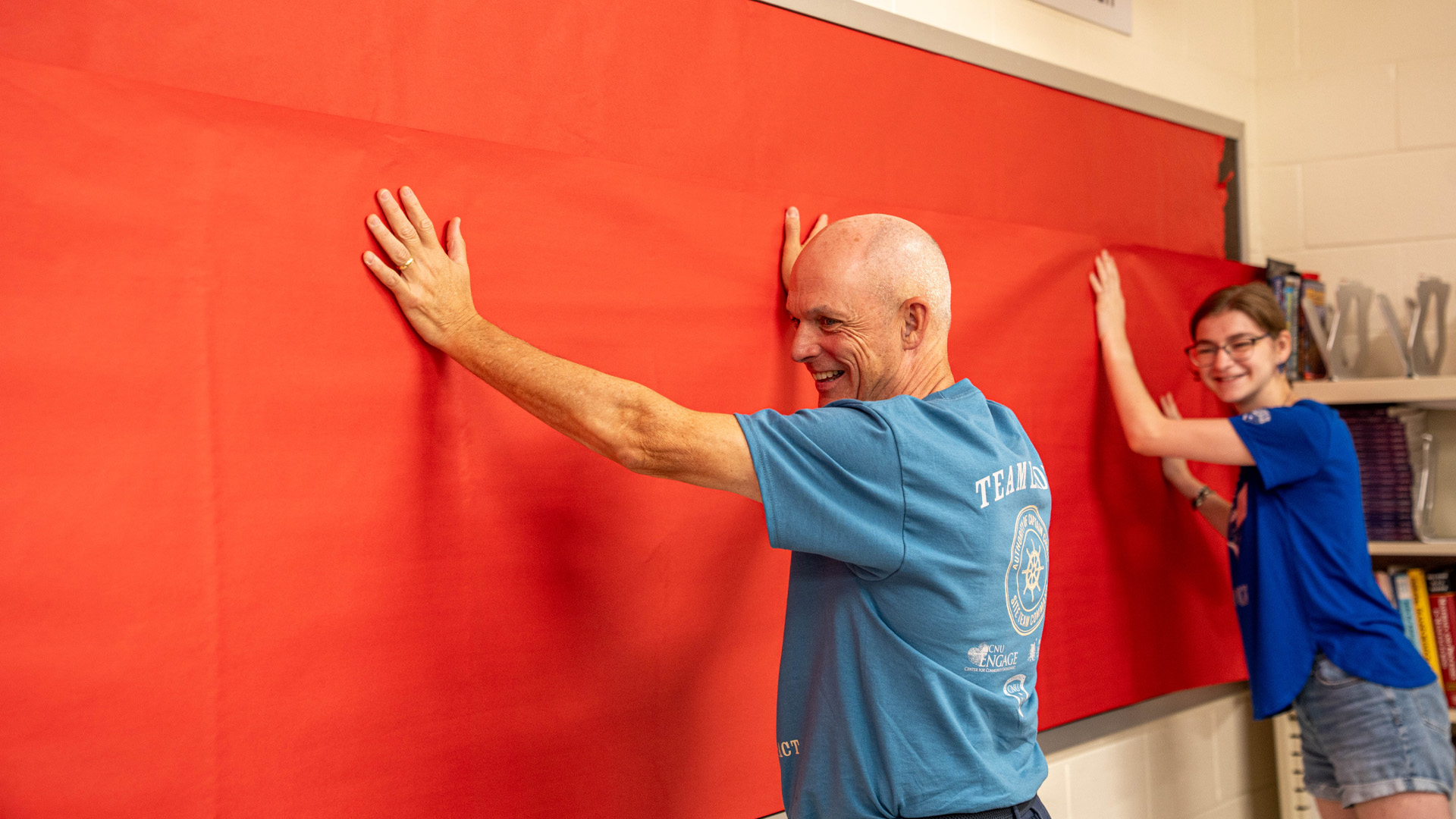 CNU President Kelly holds up paper on a bulletin board with a student