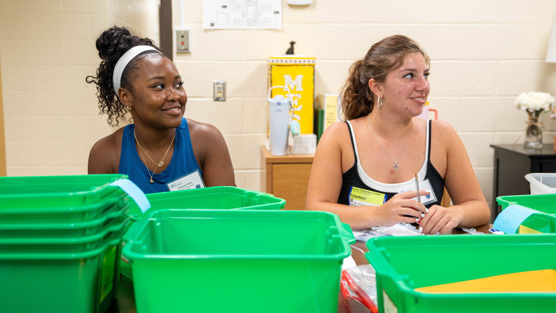 Two students sit in front of small bins