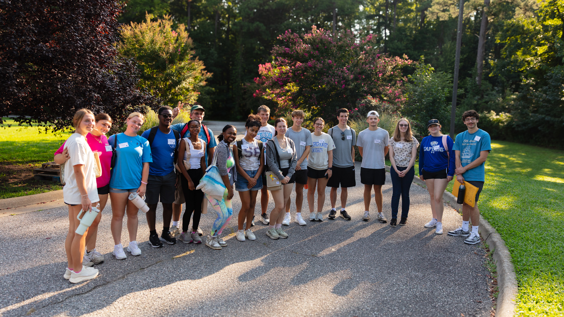 A group of students and their group leader smile for a photo outdoors