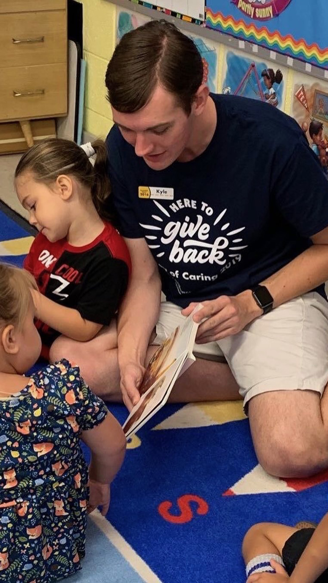 Kyle DeGood reads to young children in a classroom.