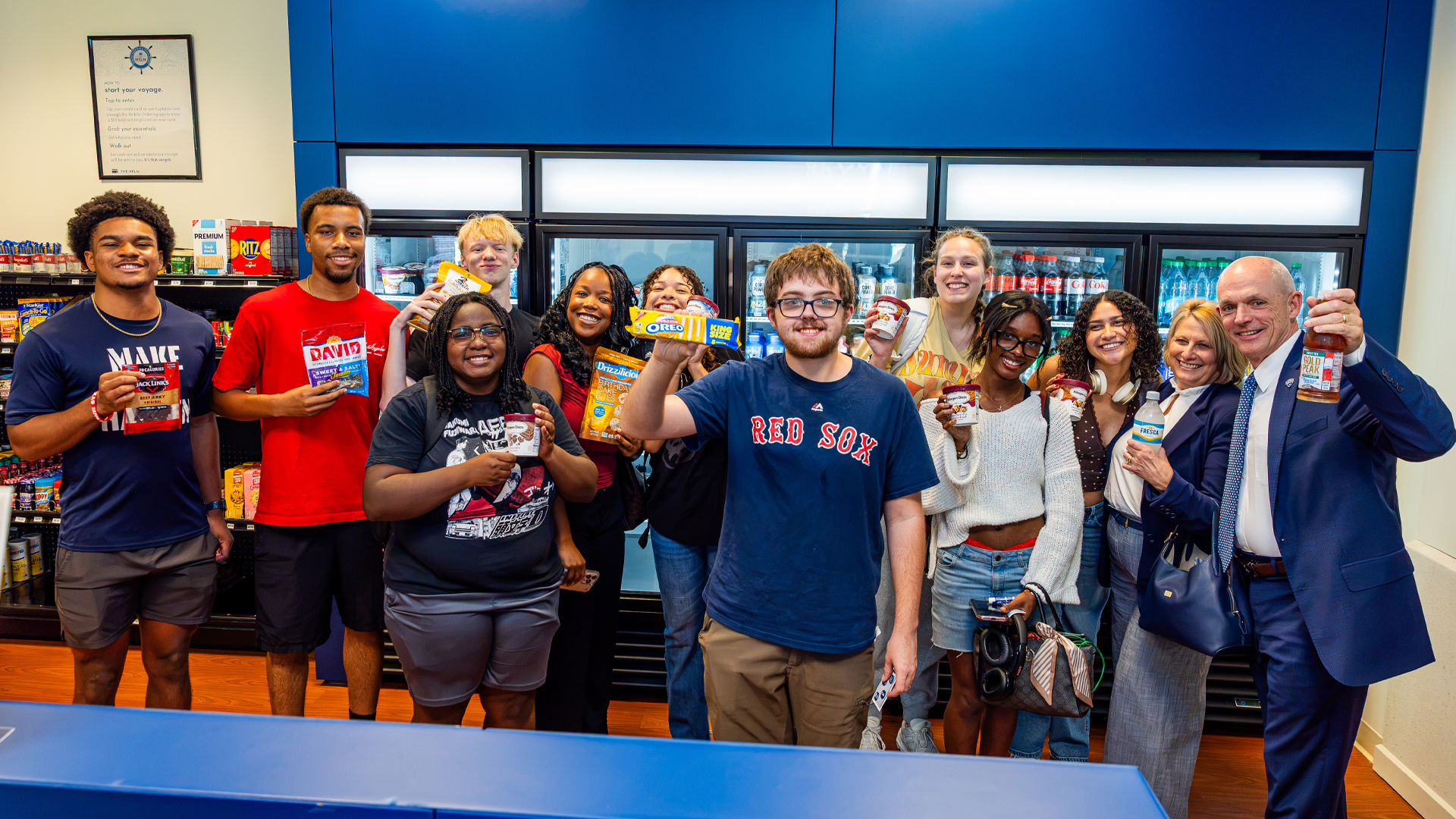 CNU students stand with various convenience store items in their hands with First Lady Angie and CNU President Bill Kelly in the new HEML convenience store on campus.