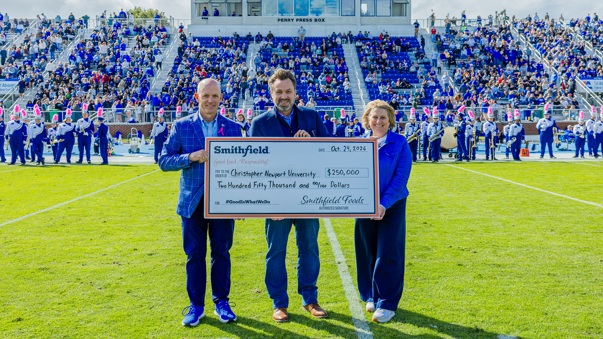 CNU President Bill Kelly, Smithfield Foods CEO and President Shane Smith and First Lady Angie Kelly hold a large check for $250,000 on a football field
