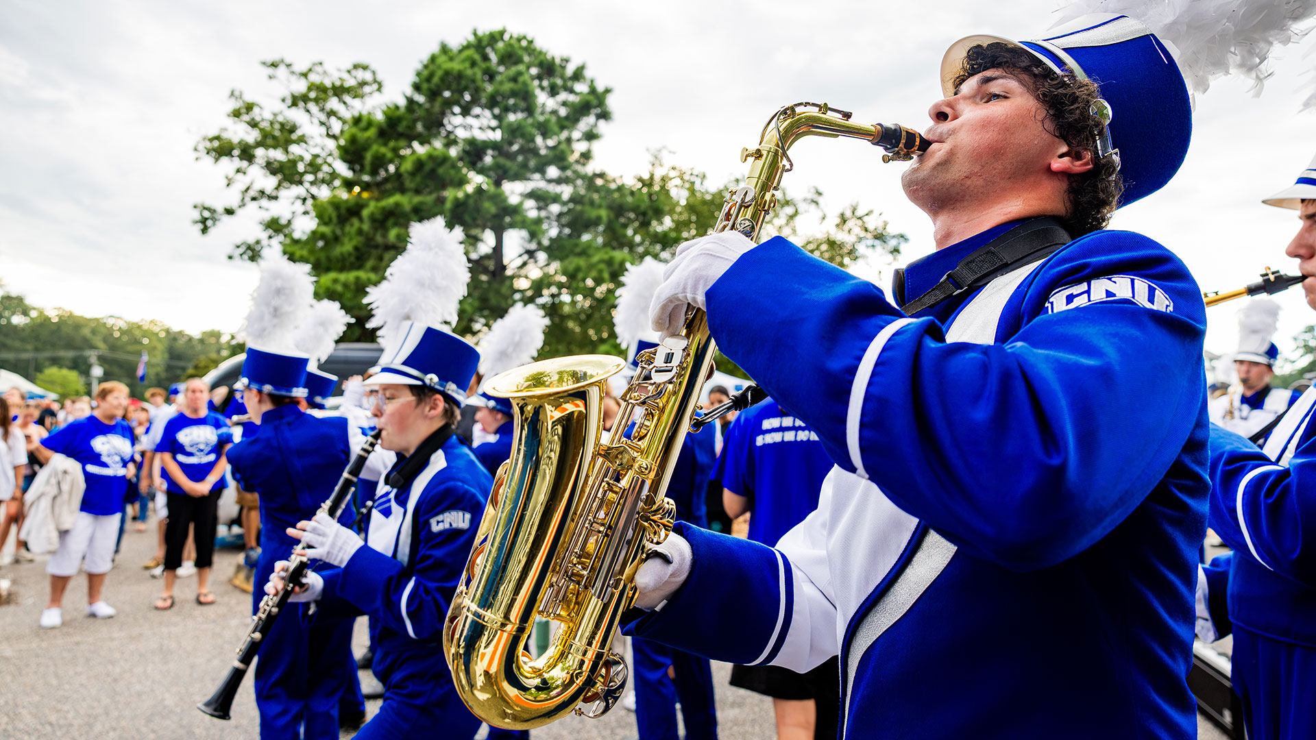A member of the Marching Captains plays their saxophone in the tailgate area.