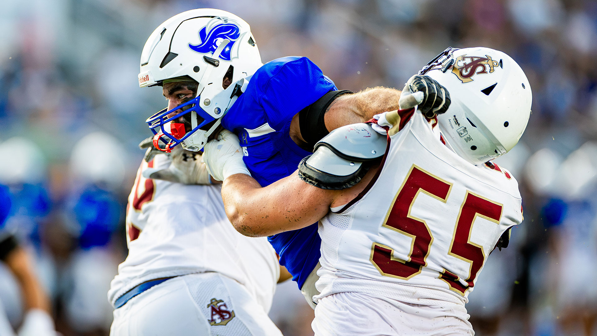 A CNU football player pushes past two opposing players.