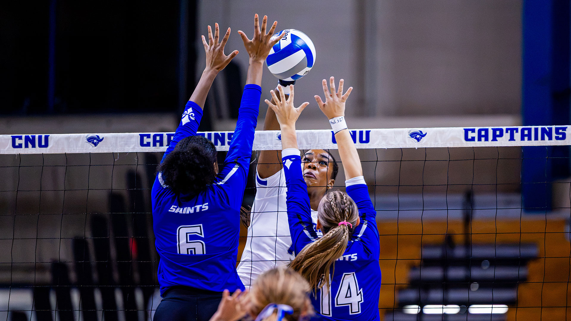 A CNU volleyball player spikes the ball between a block